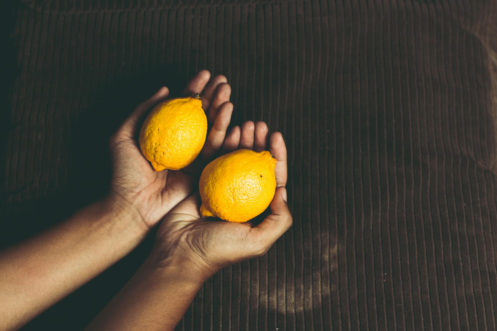 Close-up of two fresh lemons held in cupped hands, symbolizing the gentle approach of Lemon vibrators