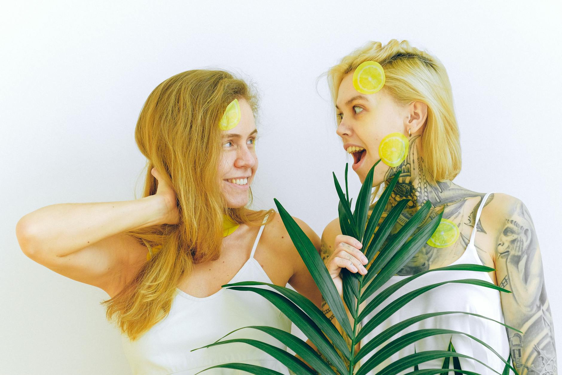 Two women smiling with lemon and tropical plants, expressing joy and connection