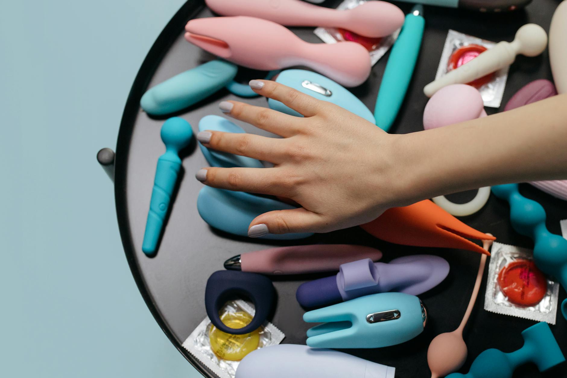 Frau mit Brille hält blaue und rosa Silikonvibratoren nachdenklich in der Hand