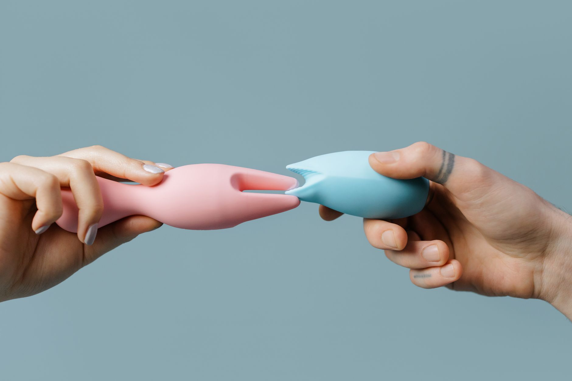 Hand hält einen blauen Vibrator gegen violetten Hintergrund, symbolisiert sanfte und bewusste Stimulation