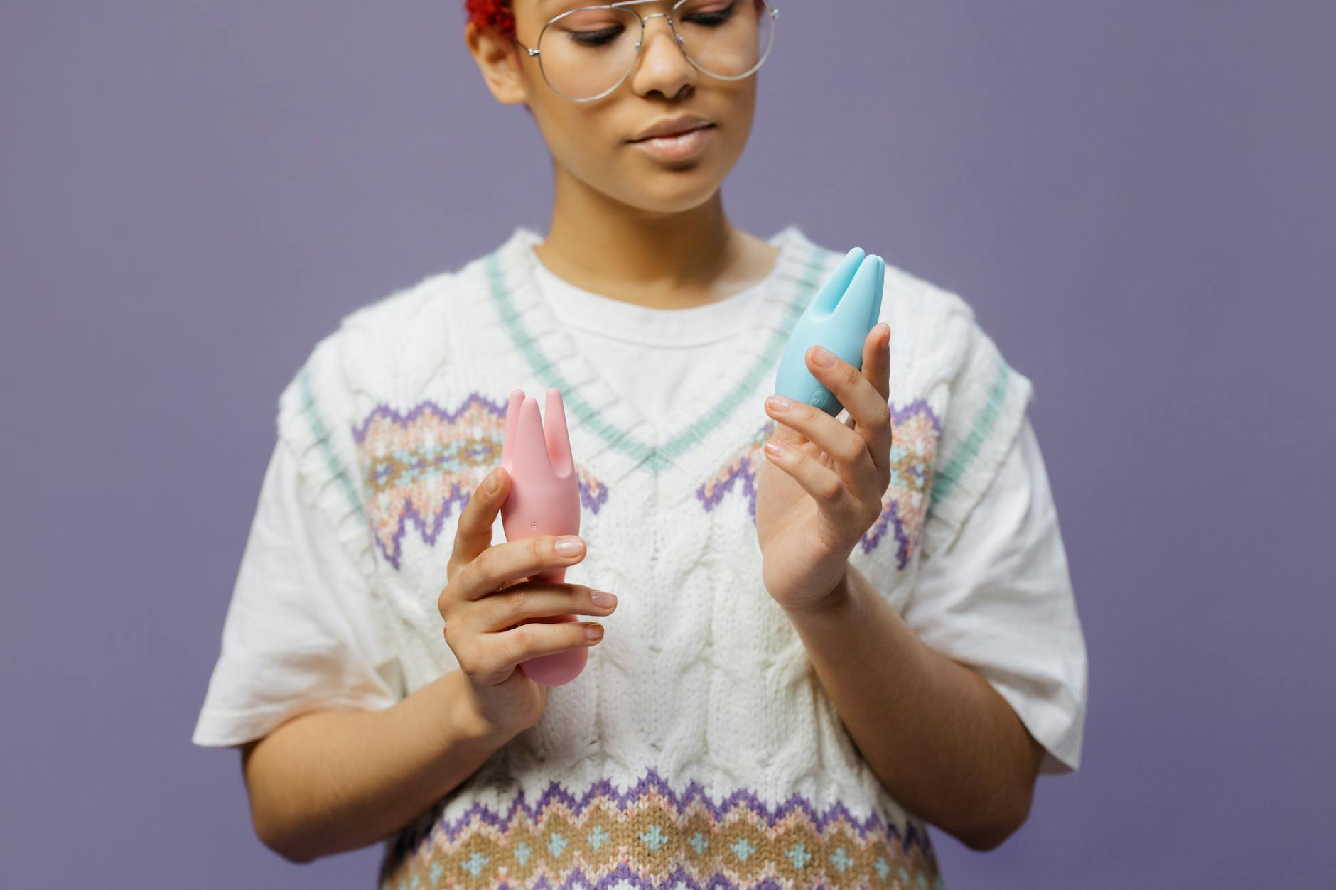 Woman holding blue and pink silicone vibrators with confident expression
