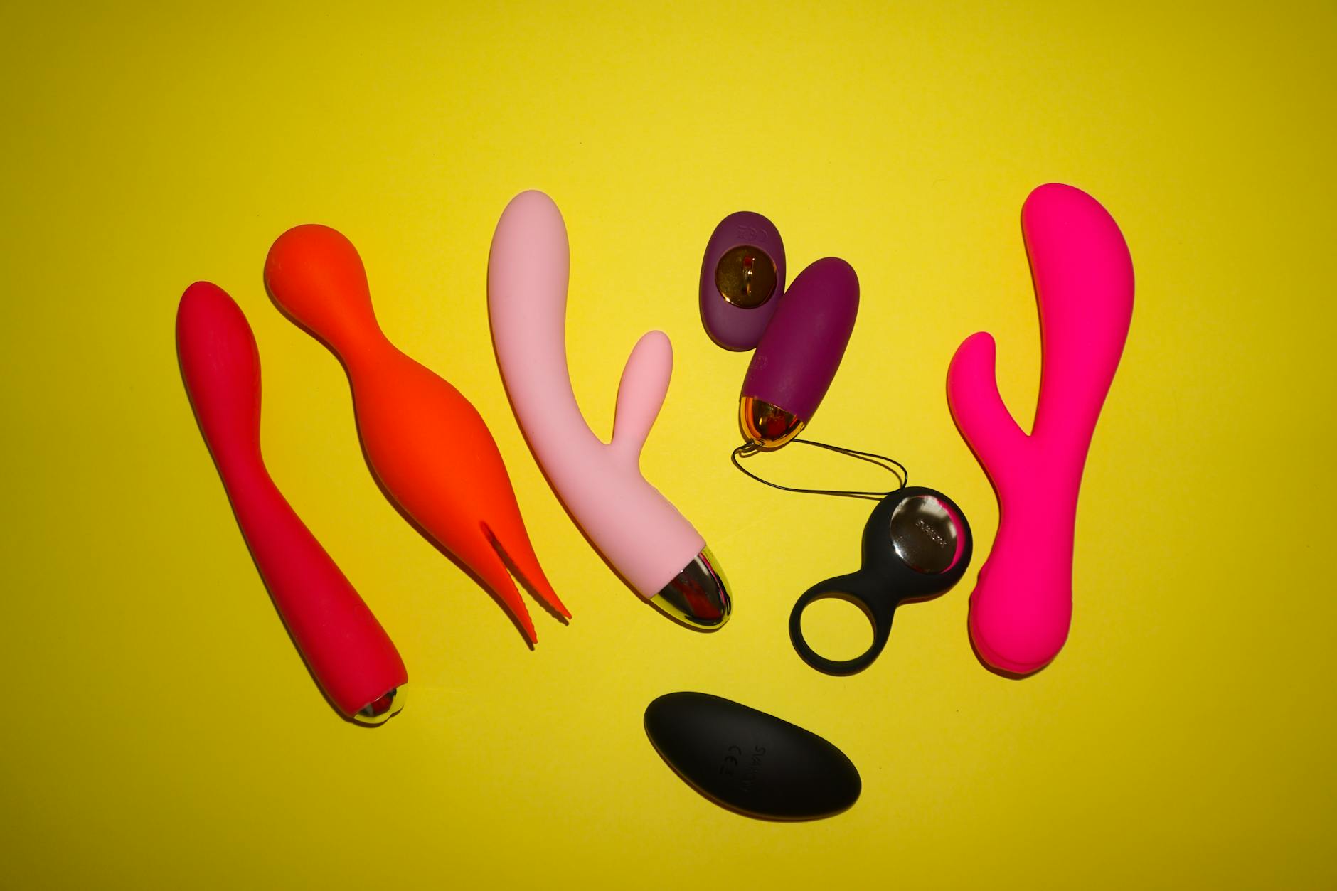 A teal silicone vibrator resting on smooth white silk fabric